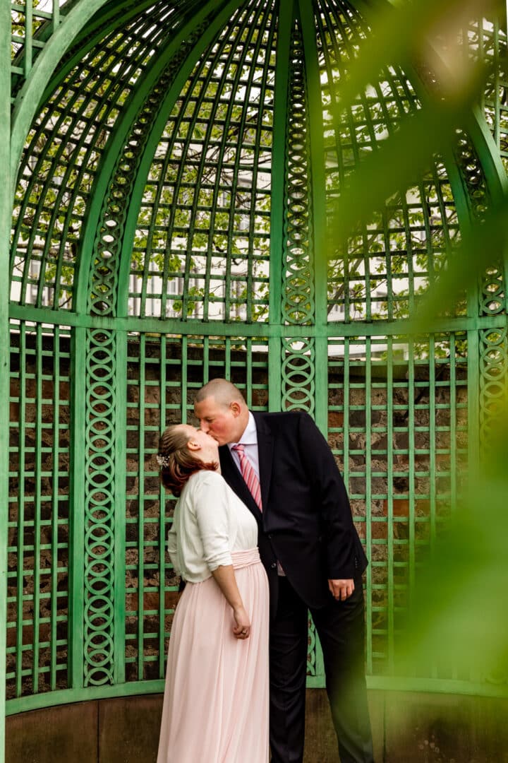 Mann küsst seine Frau mit Babybauch im Prinz-Georg-Garten Darmstadt