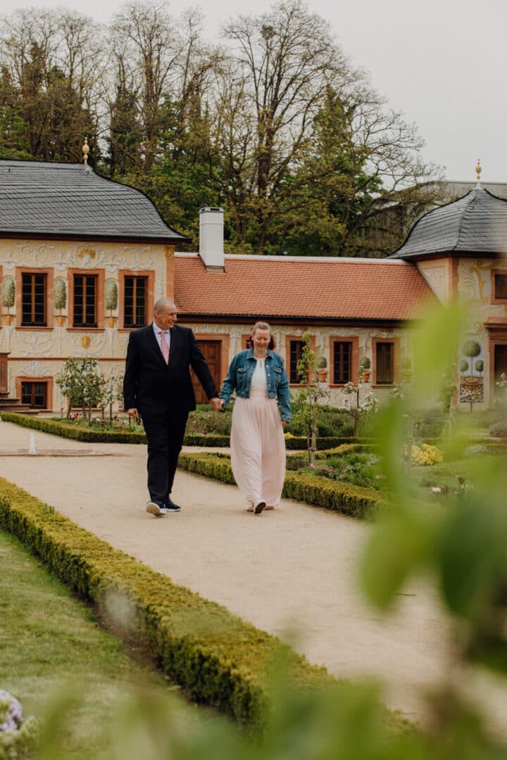 Ein Brautpaar läuft Hand in Hand einen Weg im Prinz-Georg Garten entlang