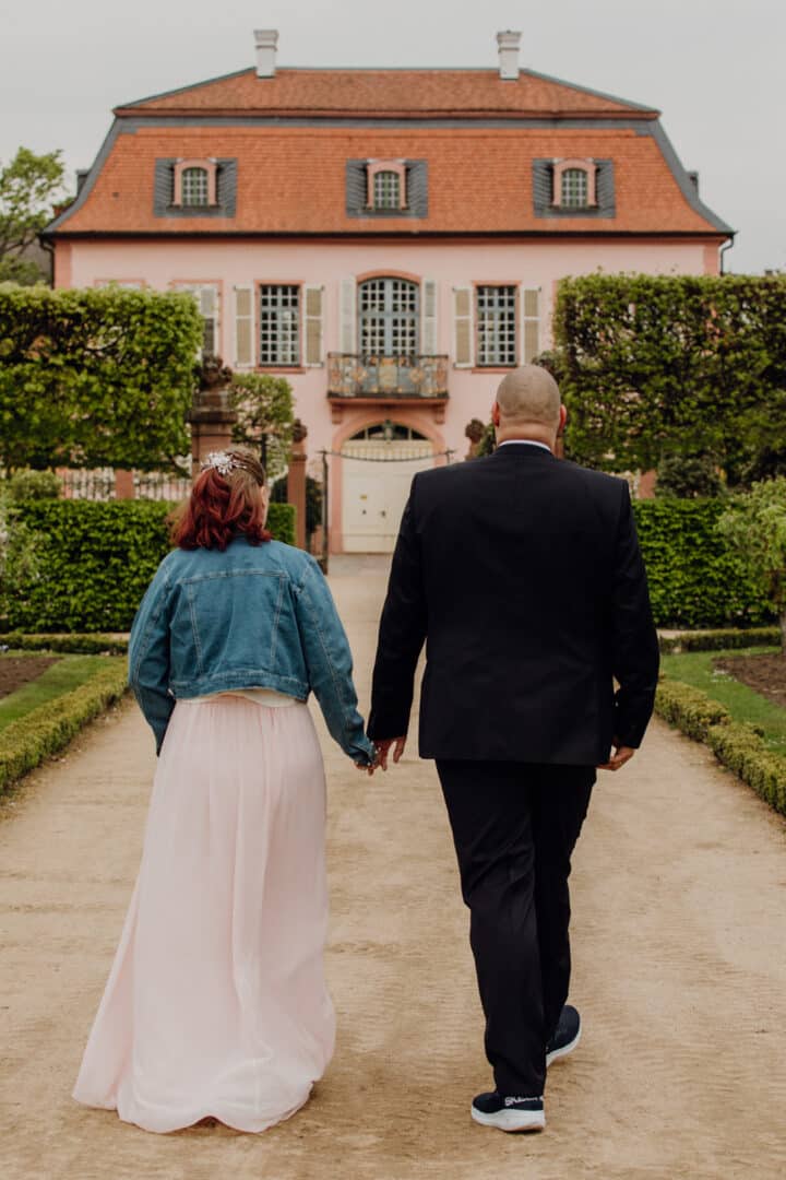 Braut und Bräutigam laufen auf ein Gebäude im Prinz-Georg Garten zu, dem Museum.