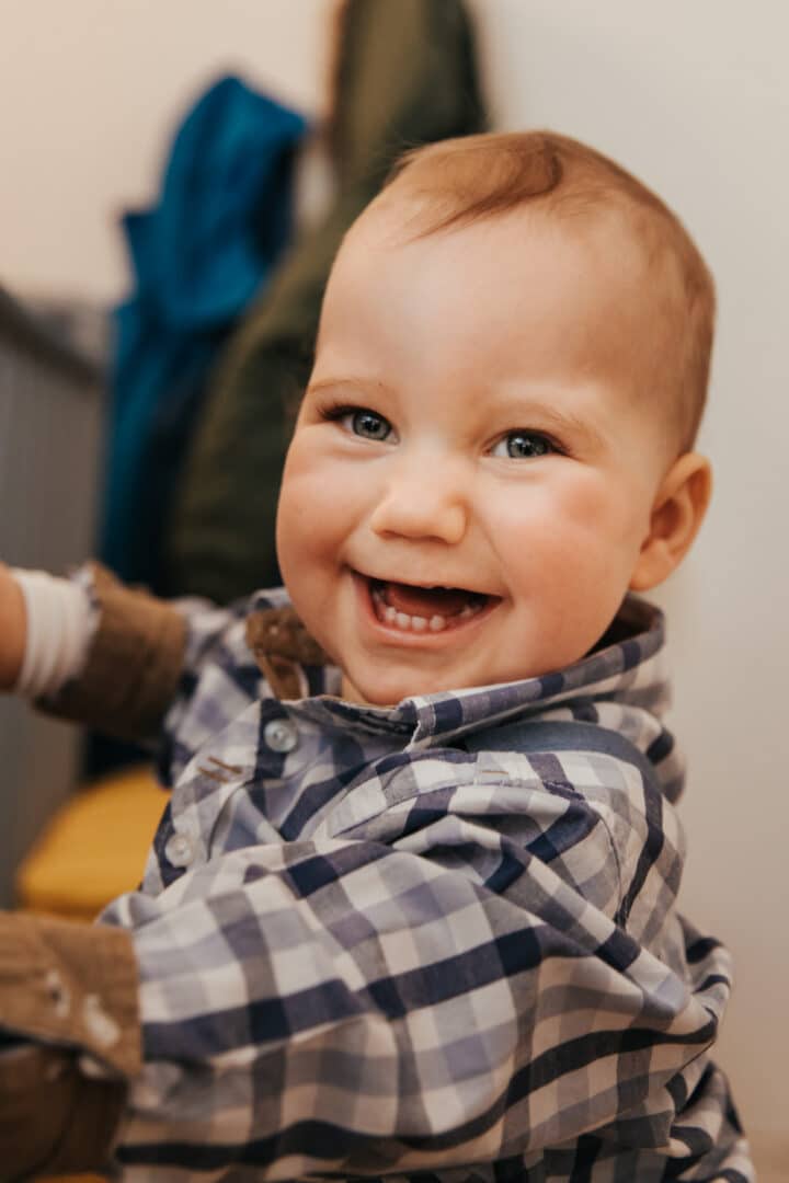 Ein kleiner Junge 1 Jahr alt lacht in die Kamera und zeigt Zähne