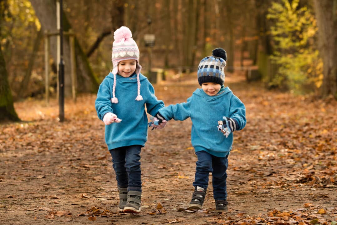 Geschwister rennen Hand in Hand im Laub bei einem Kinderfotoshooting in Darmstadt