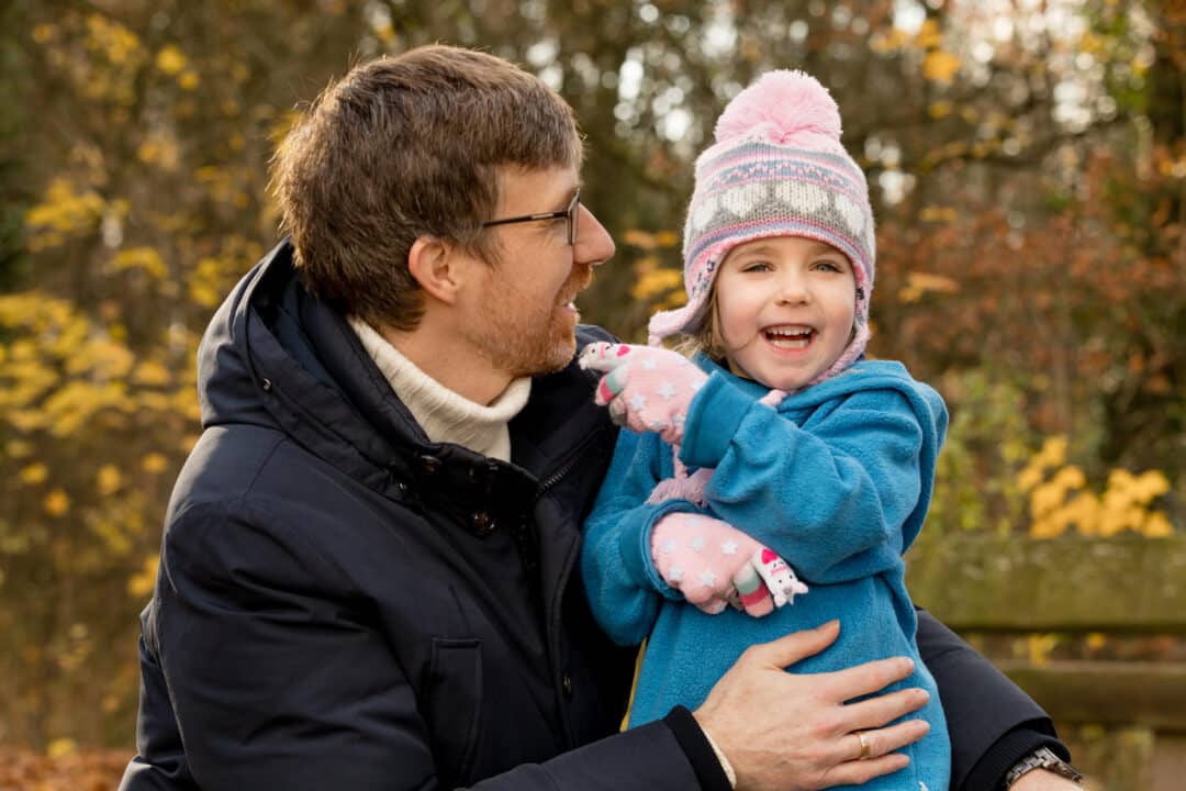 Vater hält lachende Tochter beim herbstlichen Familienshooting am Jagdschloss Kranichstein