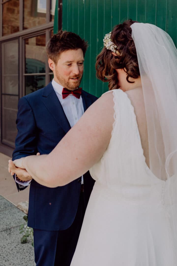 First Look und der Bräutigam schaut seine Braut fasziniert an.