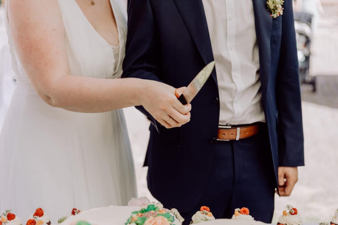 Brautpaar hält Messer in der Hand um die Hochzeitstore anzuschneiden.