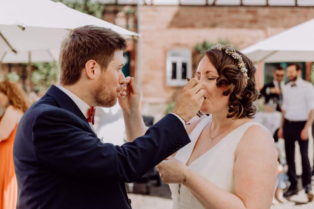 Brautpaar steckt sich Gegenseitig die Kuchengabeln in den Mund