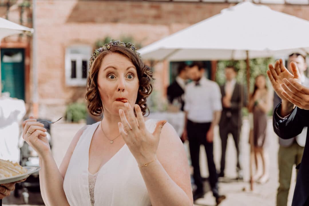 Braut macht lustiges Gesicht während sie den Kuchen isst.