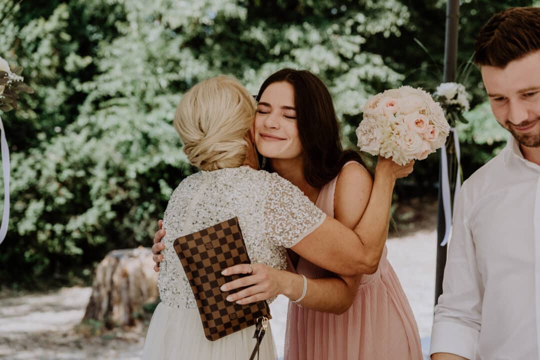 Die Tochter der Braut gratuliert ihrer Mutter zur Hochzeit mit einer Umarmung