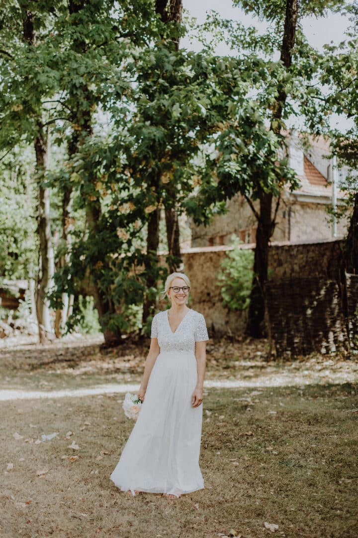Braut steht auf einer Wiese und läuft beim Fotografieren mit dem Hochzeitsfotograf
