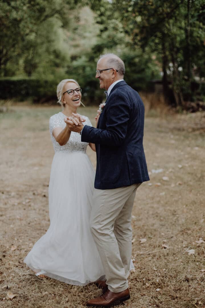 Brautpaar tanzt lachend auf einer Wiese auf dem Hofgut Dippelshof