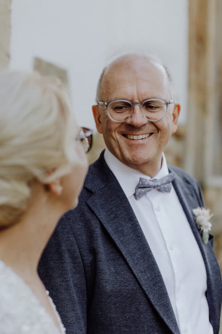 Älterer Bräutigam lacht seine Braut an beim fotografiert werden.