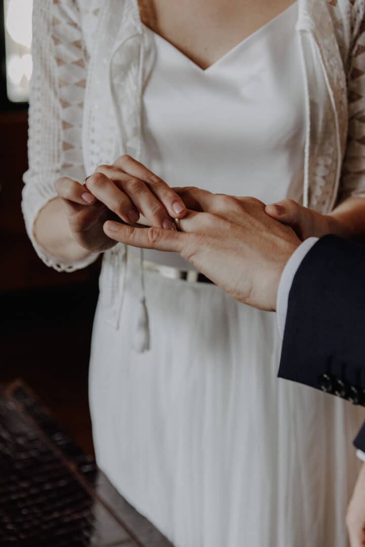 Die Braut steckt ihrem Bräutigam den Ring an.