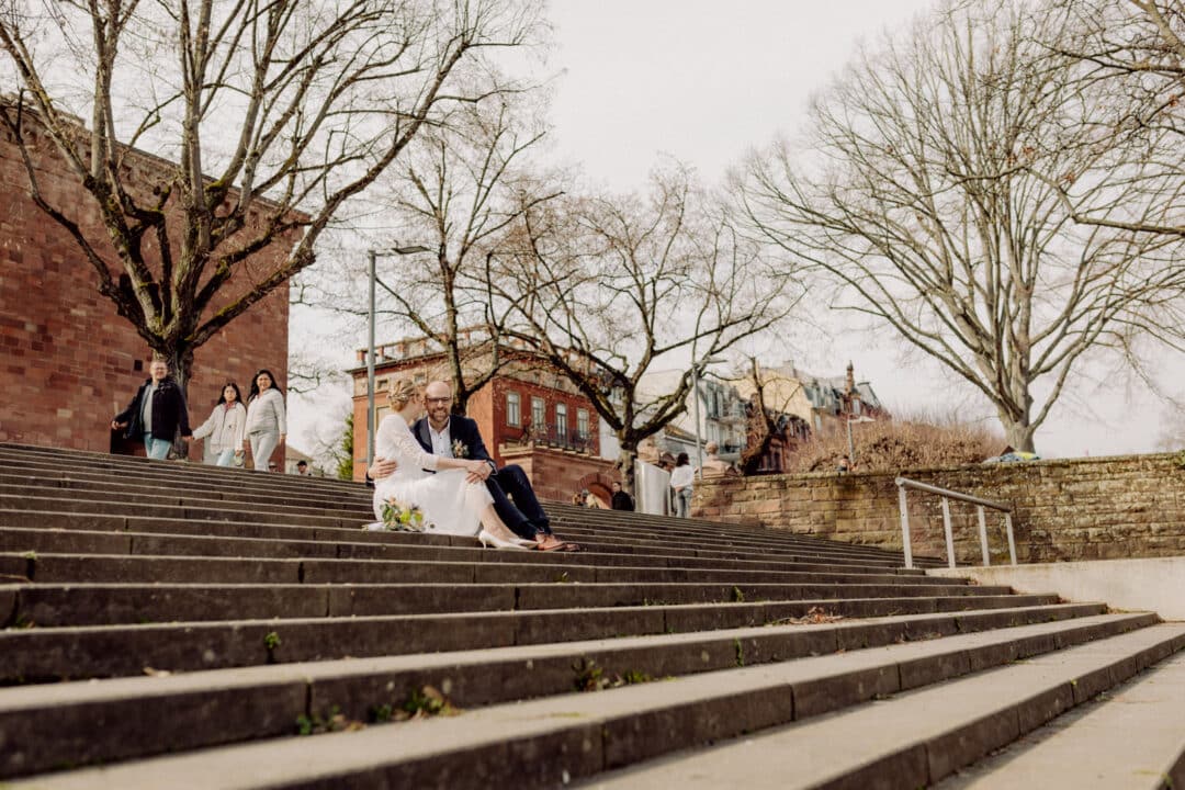 Brautpaar sitzt auf Stufen am Mainzer Rhein.