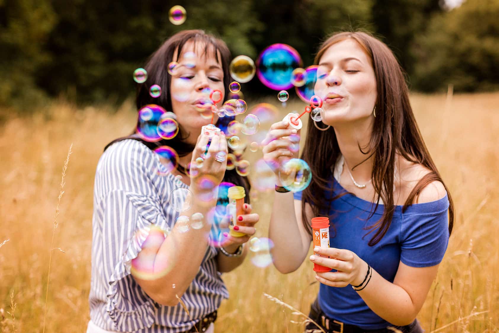 Zwei Frauen blasen Seifenblasen in einem Grasfeld auf der Rosenhoehe in Darmstadt