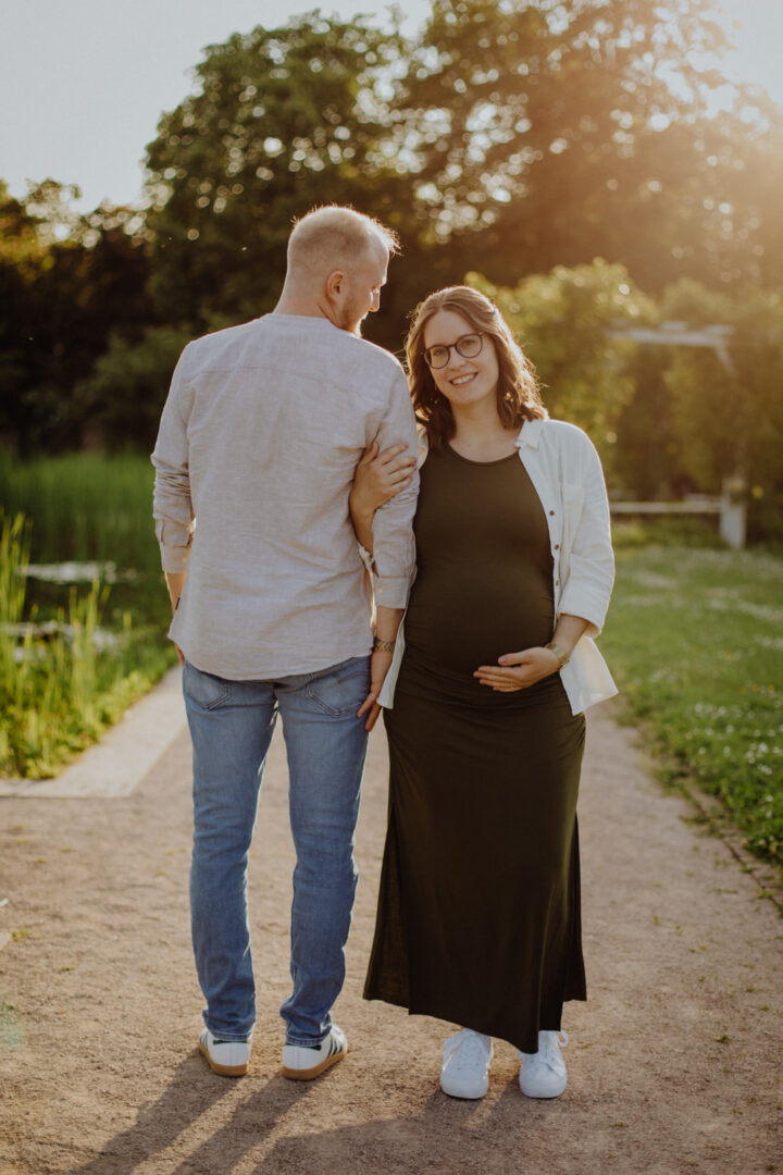 Ein Paar beim Babybauchfotoshooting in einem Park in Darmstadt beim Sonnenuntergang.