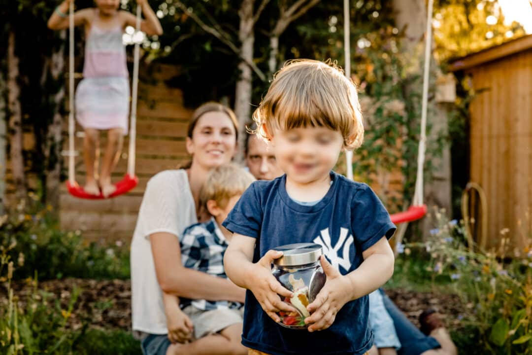 Sohn klaut Süssigkeitenglas während eines Fotoshootings mit der Familie im Garten