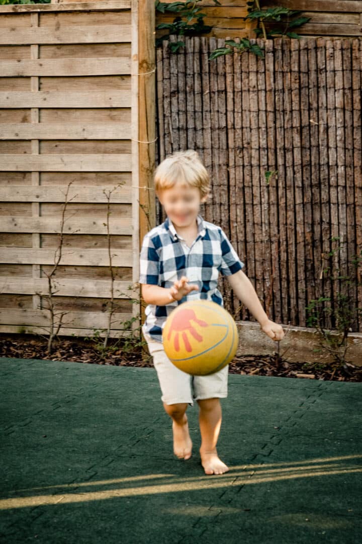 Junge spielt Basketball im Garten im Sommer