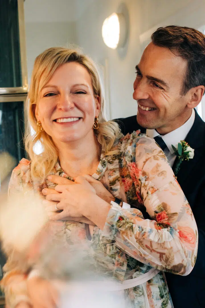 Braut lacht in die Kamera während ihr Mann sie in seinen Armen hält. Standesamt Mathildenhöhe.
