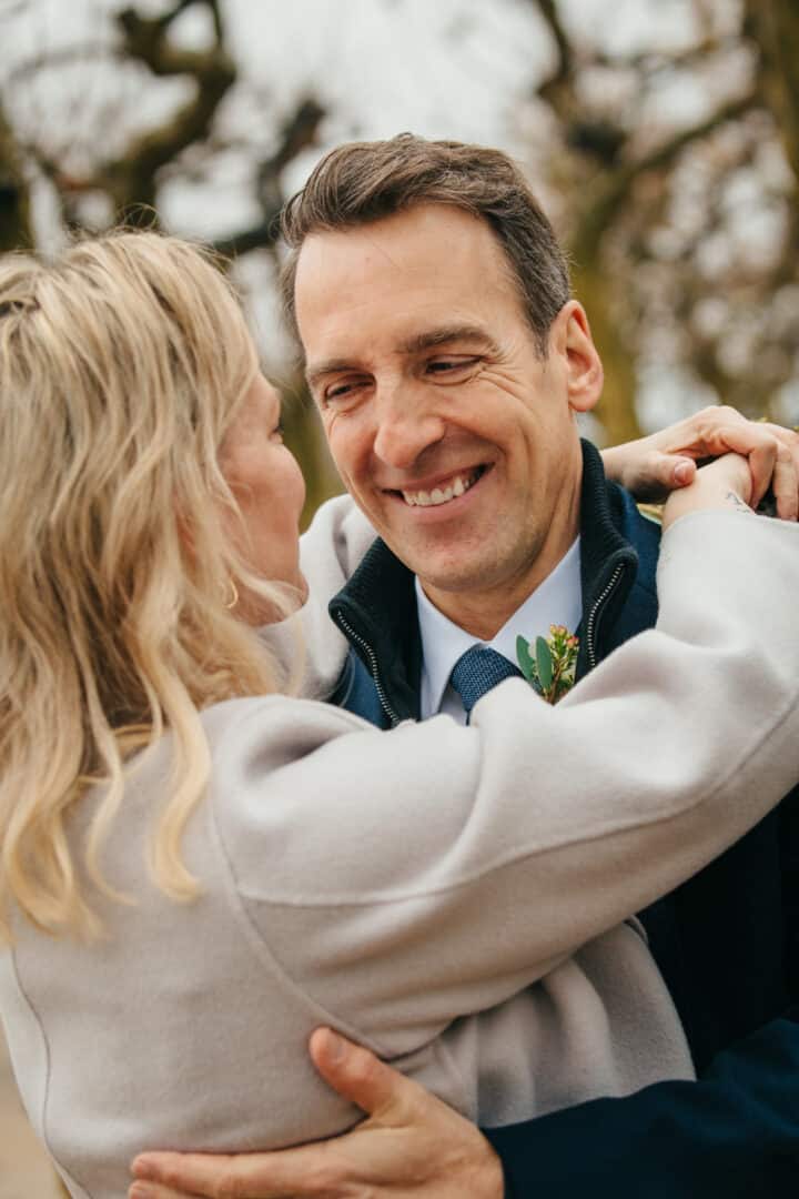 Bräutigam hält seine Frau im Arm und lacht sie an nach ihrer Trauung im Standesamt Mathildenhöhe im Winter.