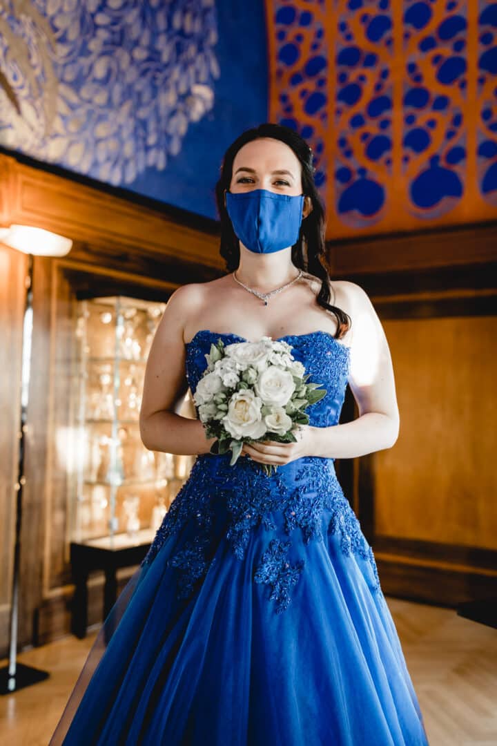 Braut mit blauer Mund-Nase Maske lacht in Kamera