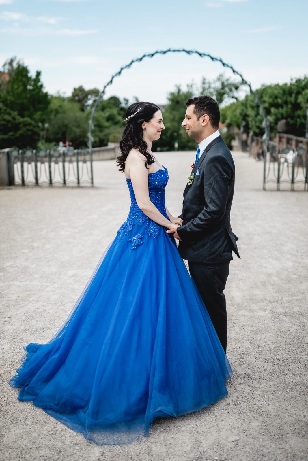 Braut im blauen Brautkleid hält ihren Mann an der Hand und sie lachen sich an