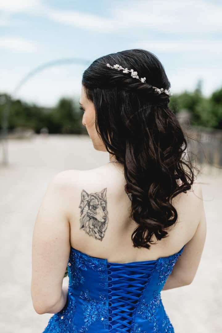 Braut im blauen Brautkleid von hinten mit Wolftattoo auf der Schulter auf der Mathildenhöhe in Darmstadt