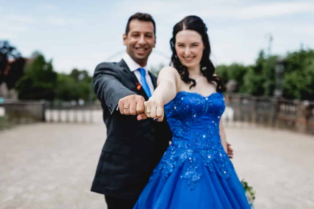 Braut in blau und ihr Mann zeigen ihre Ringe in die Kamera auf der Mathildenhöhe Darmstadt