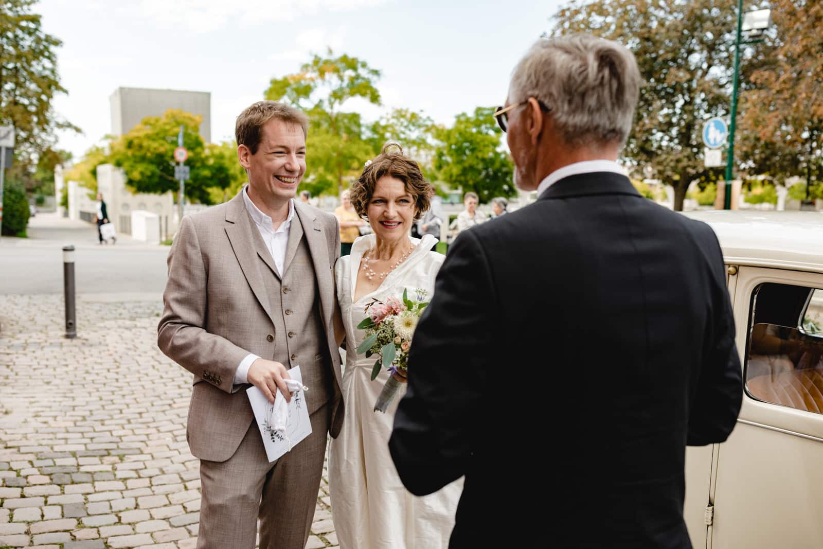 Brautpaar beim Gespräch mit dem Oldtimer Brautauto Fahrer vor der St. Ludwig Kirche in Darmstadt.