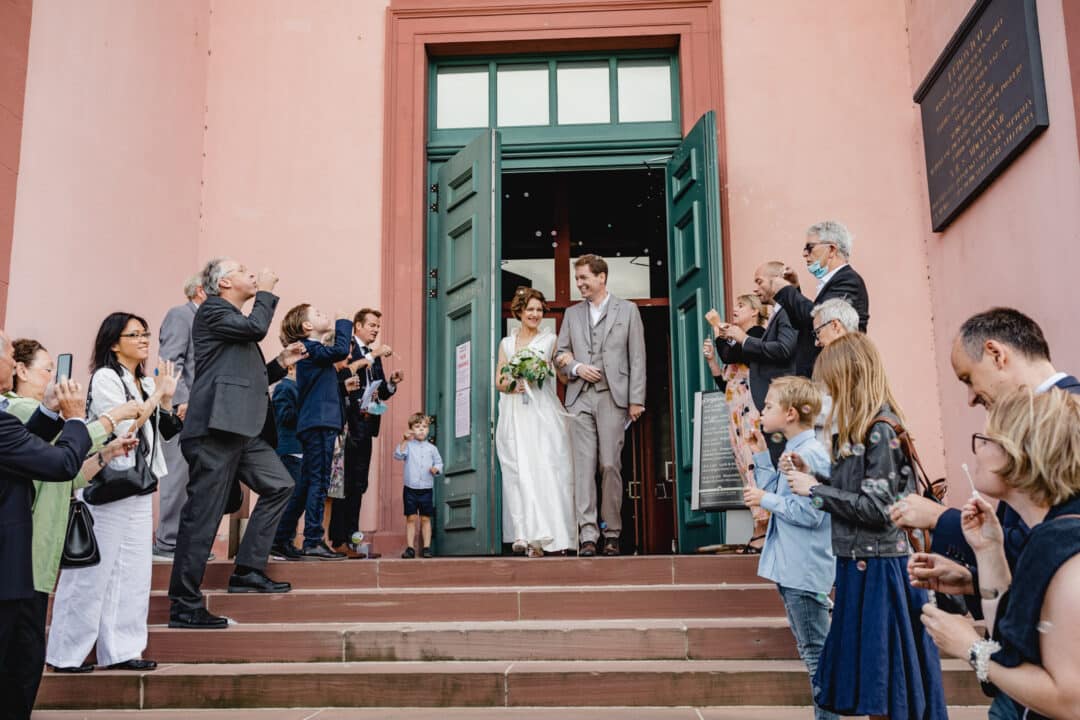 Brautpaar kommt aus der St. Ludwig Kirche in Darmstadt und die Gäste blasen Seifenblasen.