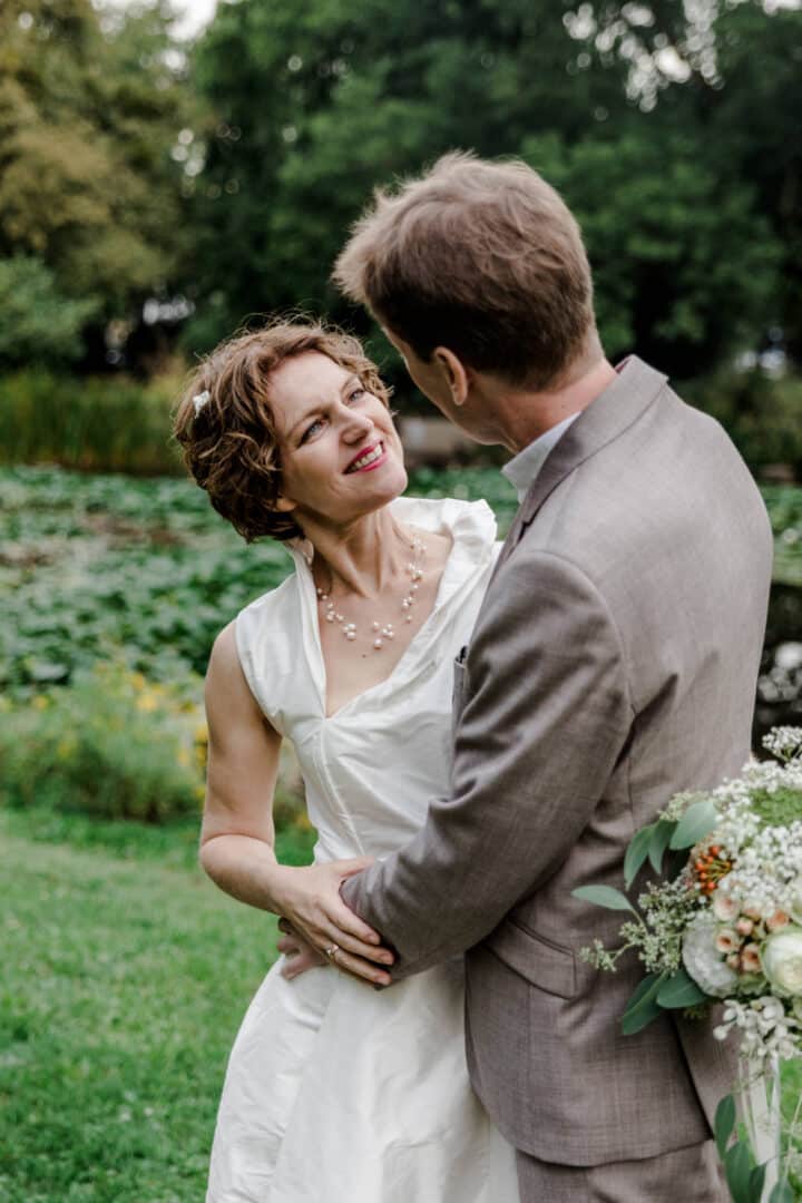 Braut lacht ihren Mann bei Brautpaarshooting im Park des Prinz-Emil-Schlösschen in Darmstadt an