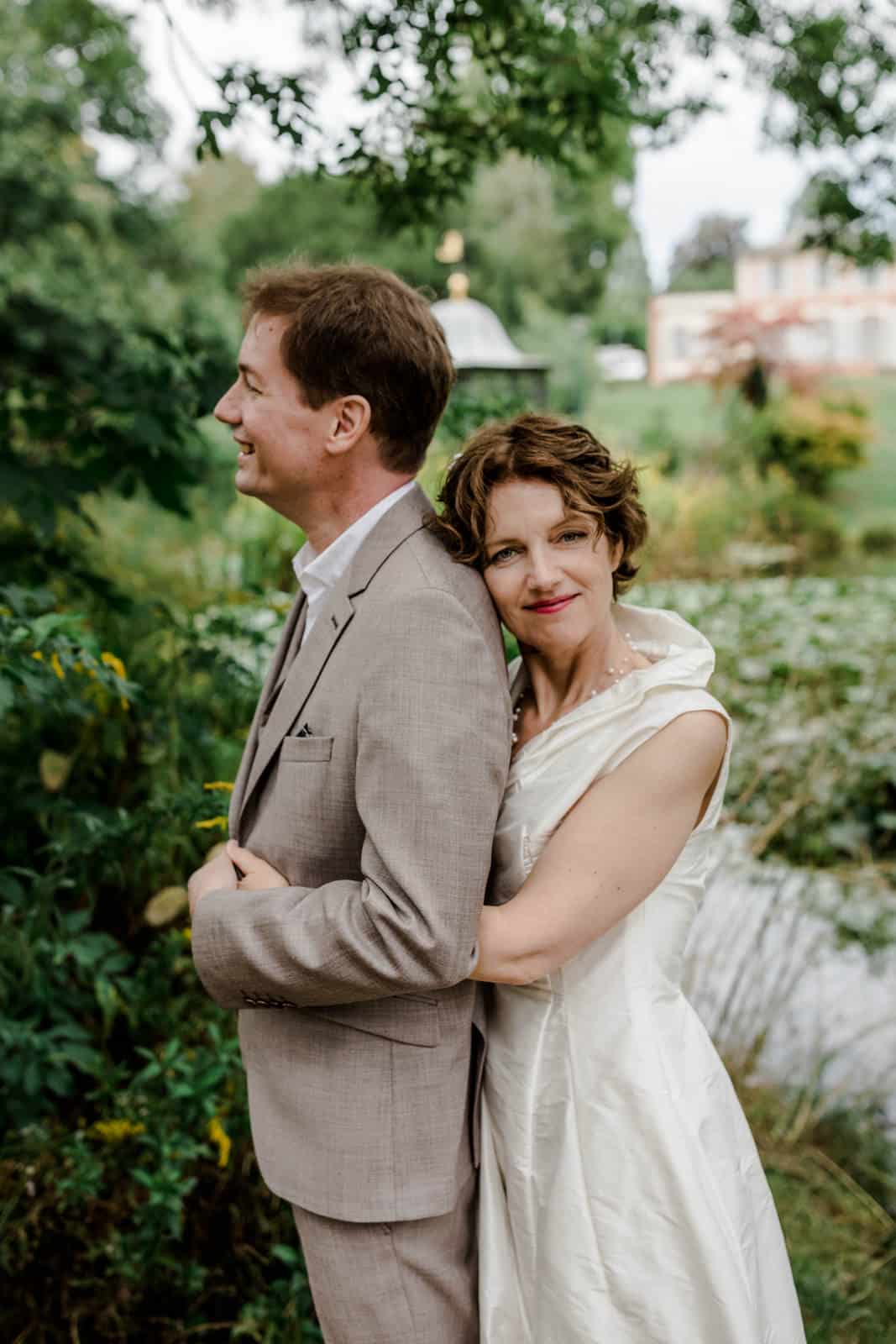 Braut kuschelt sich an die Schulter ihres Mannes im Park des Prinz-Emil-Schlösschen in Darmstadt