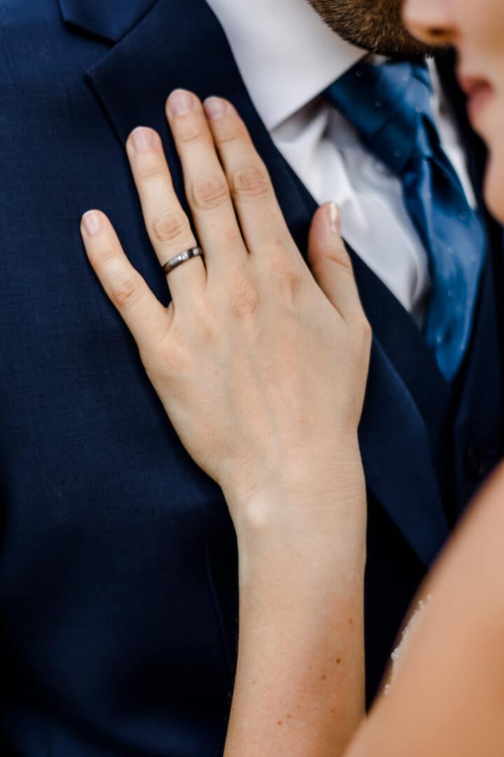 Nahes Fotos von Hand mit Ehering liegend auf dem Anzug des Ehemanns