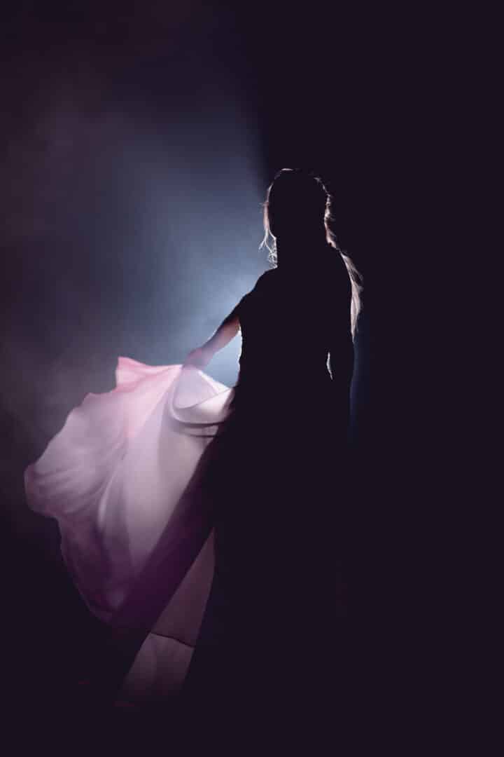 Braut wirft im Schatten des Scheinwerferlichts ihr Kleid hoch.