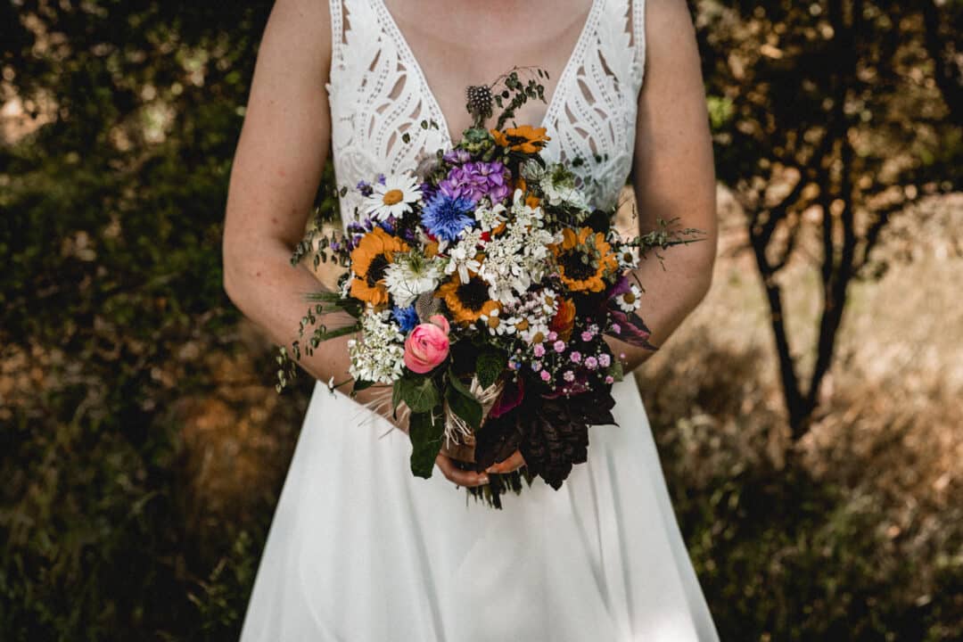 Brautstrauss einer Vintagebraut in den Griesheimer Dünen mit Sonnenblumen und Kornblumen und Margeriten