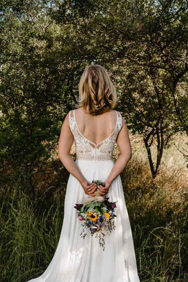 Braut beim Portraitshooting von hinten mit Brautstrauss und schönem freien Rücken