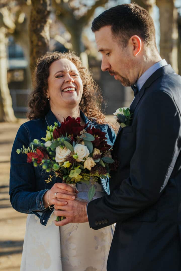 Braut und Bräutigam halten den Brautstrauss in der Hand und Braut lacht auf der Mathildenhöhe in Darmstadt