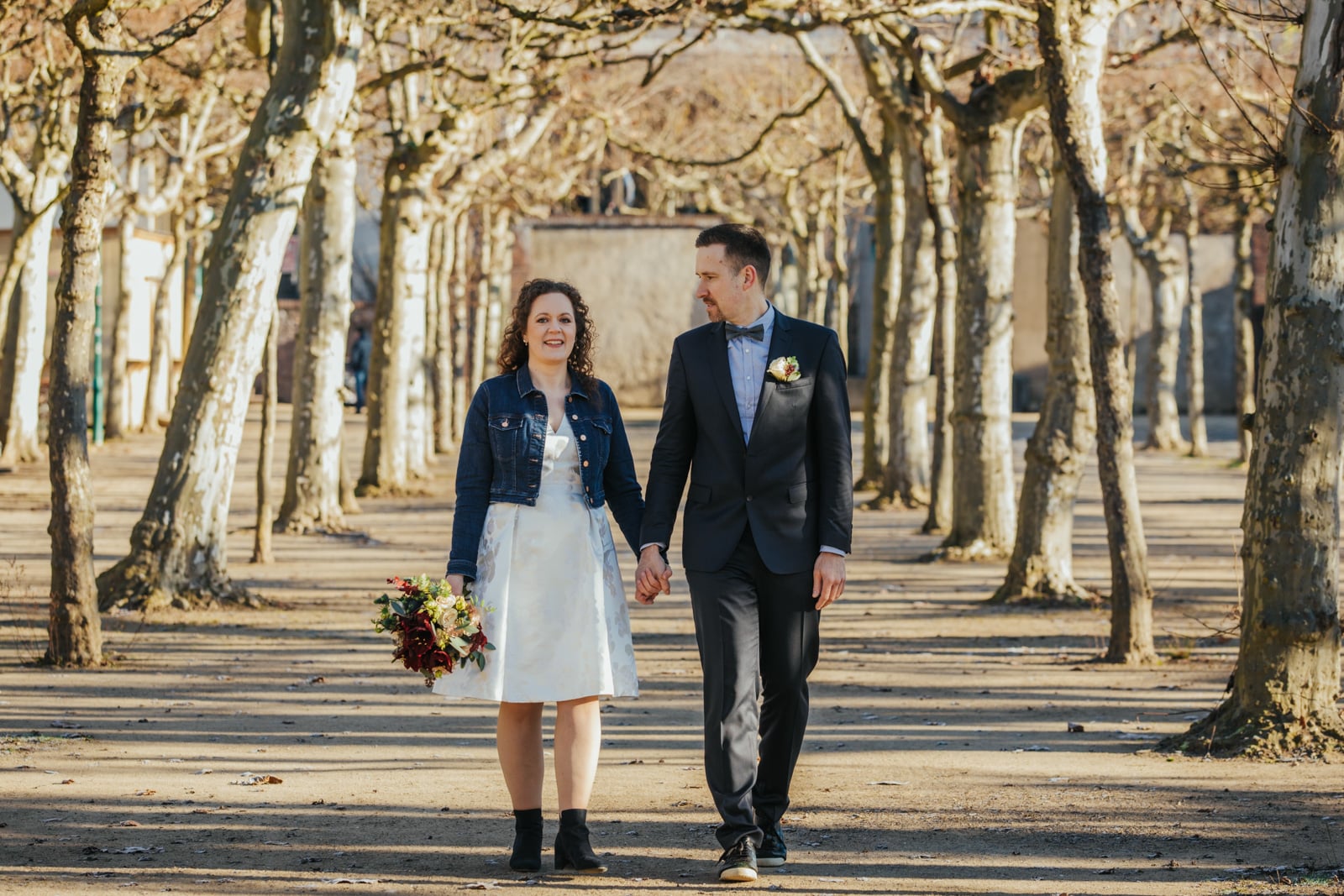 Brautpaar läuft Hand in Hand nach ihrer Hochzeit im Plantanenhain auf der Mathildenhöhe Darmstadt
