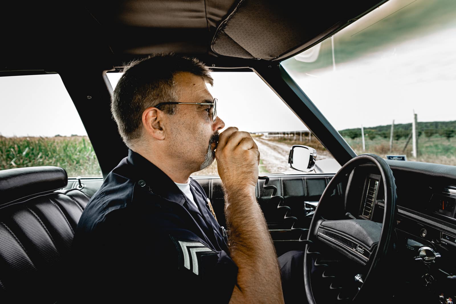Ein amerikanischer Polizist sitzt in seinem Streifenwagen und spricht in sein Funkgerät in Gross-Gerau