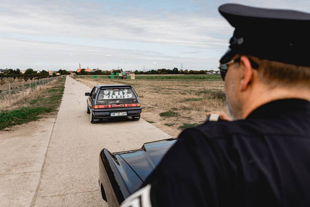 Ein amerikanischer Polizist hält einen Oldtimer Honda mit der Aufschrift Just Married an