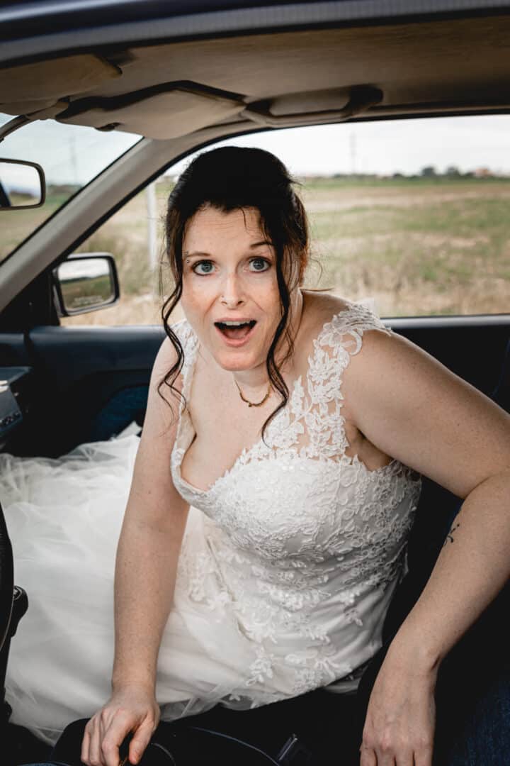 Braut schaut erschreckt in die Kamera und sitzt im Auto
