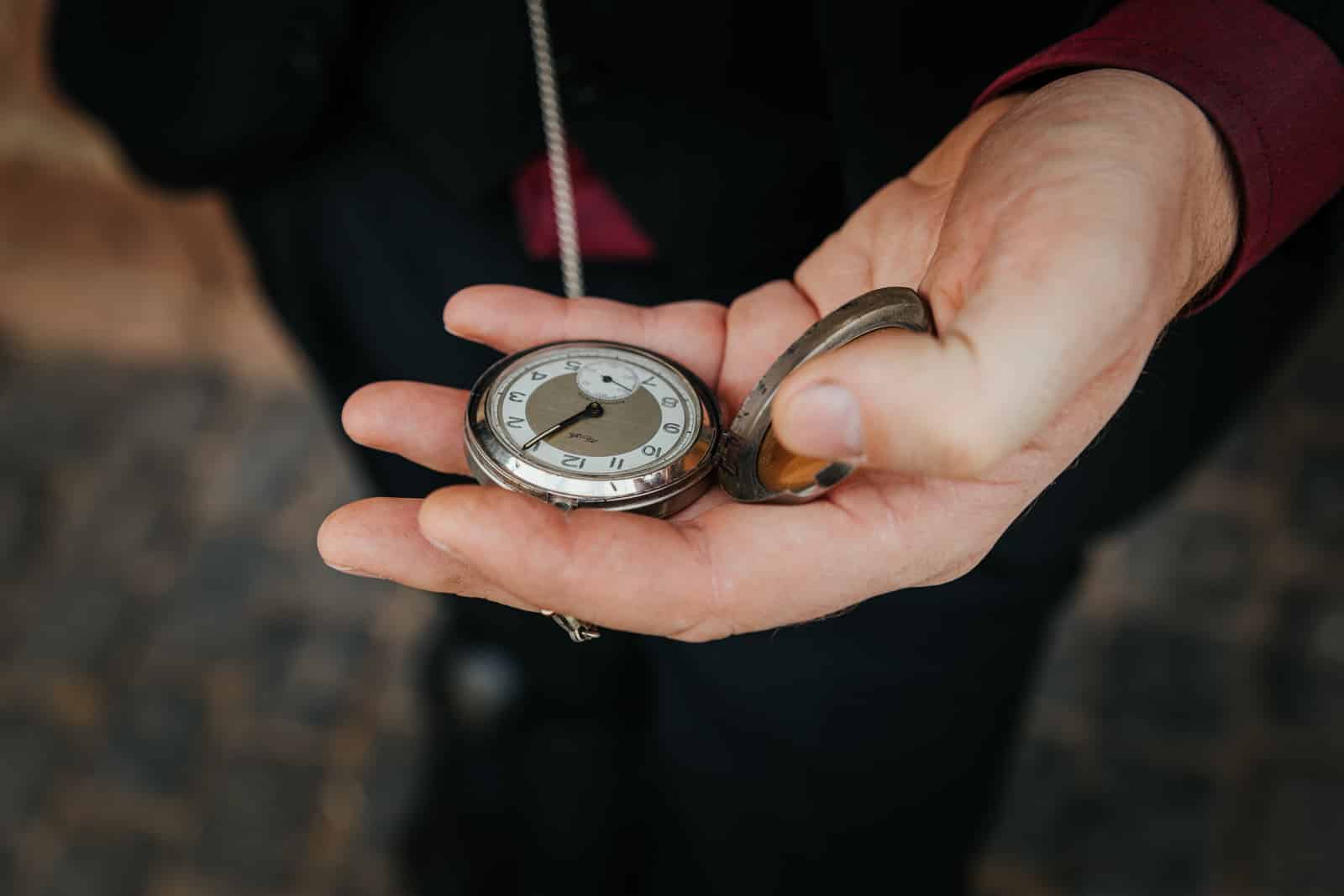 Mann hält eine alte Taschenuhr in der Hand